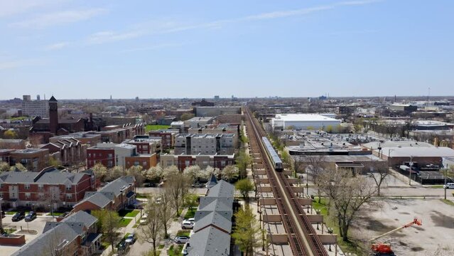 Subway in subway line purple rides on an elevated track past the United Center and a brand new residential area in Chicago on a clear sunny day. Steady wide drone shot