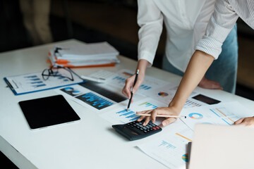 financial, Planning, Marketing and Accounting, Asian woman Economist using calculator to calculate investment documents with partners on profit taking to compete with other companies