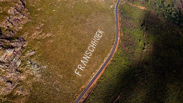Rotating aerial shot over Franschhoek place name on mountainside of pass