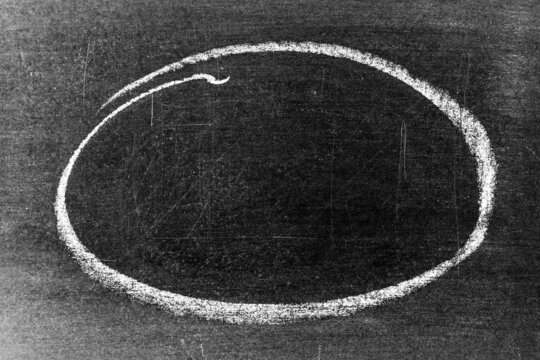 White chalk hand drawing as circle or round shape on blackboard or chalkboard background with copy space