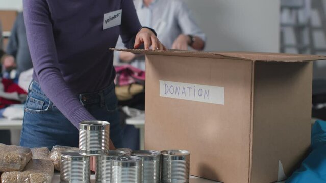 Cropped shot of woman pack food in cardboard box for donation
