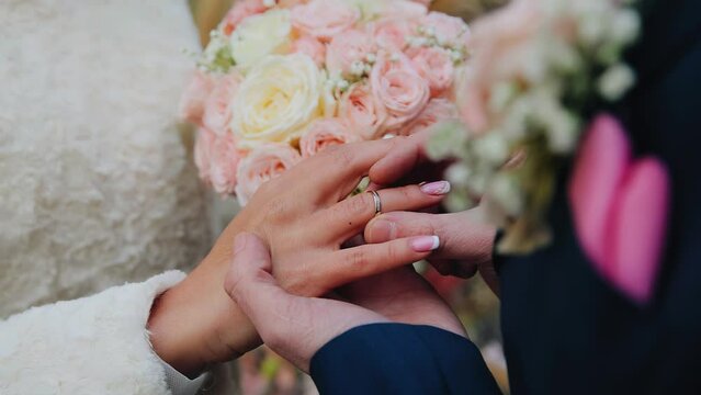 A man puts a wedding ring on his wife's hand. Shooting with a close-up of the hands