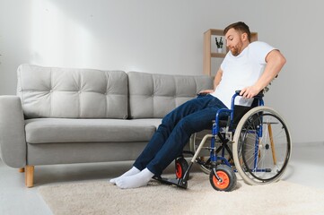 disabled man at home tries to get to his feet in a wheelchair. The concept of rehabilitation after injuries and car accidents