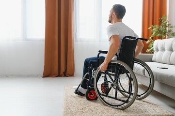 Young sad man in a wheelchair at home