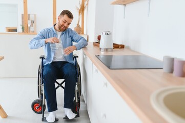 Disabled Young Man in Wheelchair Preparing Food In Kitchen.