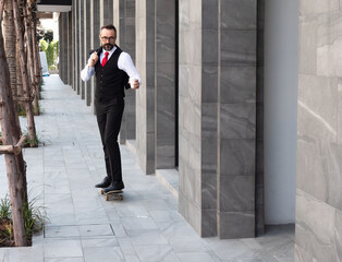 Hipster businessman is holding a paper cup with coffee skateboarding to office district. Handsome beard guy businessman entrepreneur enjoys riding a skateboard in the city.