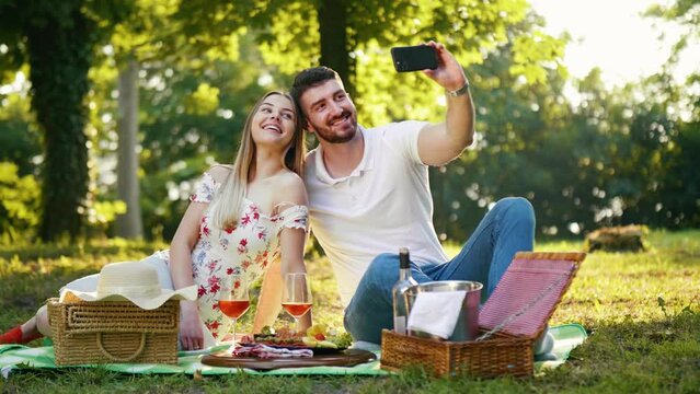 Young couple in love enjoys a picnic taking selfie photos using the phone