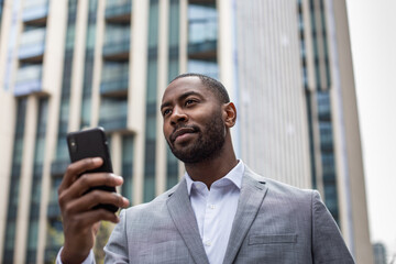 Businessman walking in city using smartphone