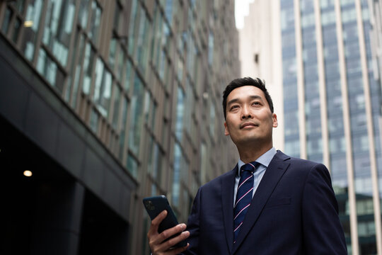 Businessman walking through city using smartphone
