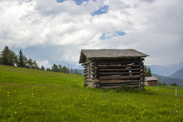 Obraz premium View of alpine landscape in summer with barn house surrounded by a green field.