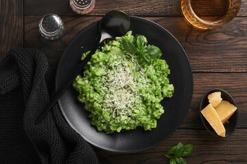 Italian risotto. Delicious risotto with pesto sauce or wild garlic pesto, basil, parmesan cheese and glass of white wine on old wooden table background. Italian dinner. Top view with copy space.