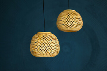 two rattan chandeliers on blue wall background. Straw lampshade in modern living room. Eco-friendly...