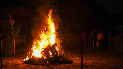 A giant bonfire lit for the auspicious festival of Holika Dahan or Lohri or Holi. The fire is surrounded by people enjoying the festival. Hindu festival