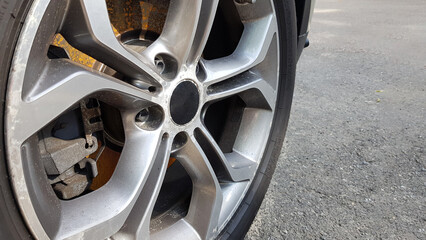 The original alloy wheel, dirty and scratched on the car close-up. Worn car wheels are waiting for...