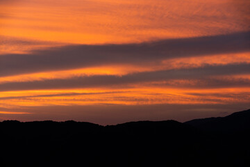 The sky is beautiful in the evening with orange clouds on the shadow of the mountains.