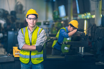 The yellow safety helmet engineer standing and smile in front of machinery and other worker doing sone work