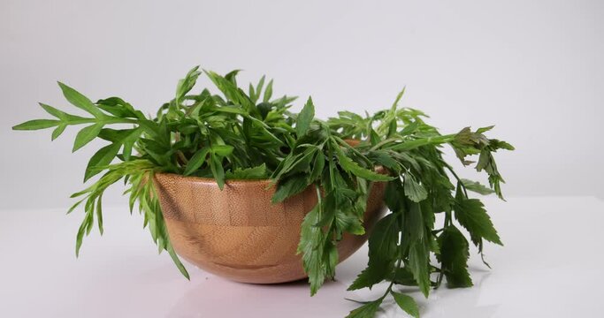 Malaysian Malay herbal leafy appetizer dish daun ulam raja selom lovage in small wooden bowl on white background