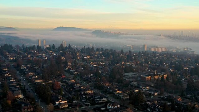 Stunning Sunset Fog over North Vancouver Neighborhood Homes and Rental Apartments in Canada - Drone Aerial Forward Flying in the Sky, Wispy Clouds and Orange Teal Colors, SFU and Mount Baker, in UHD.