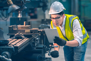 The white safety helmet engineer use tablet for a turn the a machine follow instruction in the...