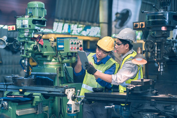 The worker teammate engineer white and yellow safety helmet working together and discussing and white helmet order to teammate as follow instruction on tablet with machinery