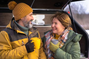 Coffee break during journey mature couple relax moment together at mini camper. Middle aged couple...