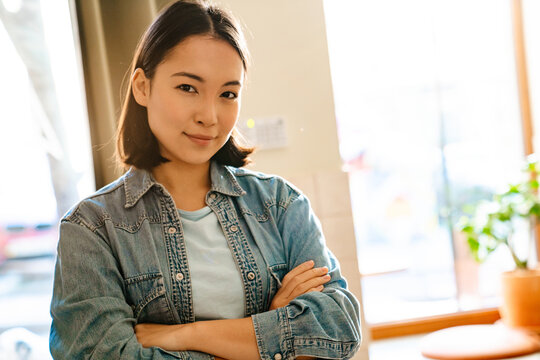 Young asian woman wearing denim shirt smiling and looking at camera