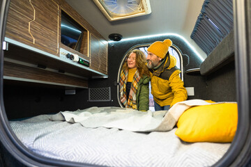 Looking news on tv mature couple in camper traveling. Man hold woman happy, pleasant smiling...