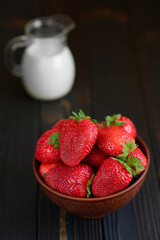 A bowl of red juicy strawberries on rustic wooden table. Healthy and diet snack food concept.