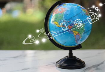 a world globe with internet of things icon on white table in soft green nature background.