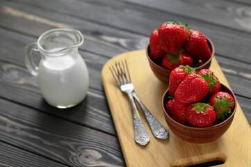 A bowl of red juicy strawberries on rustic wooden table. Healthy and diet snack food concept.