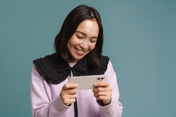 Young asian woman playing online game on mobile phone