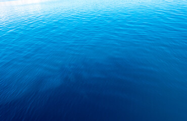 Clear water texture in blue and orange. Background of the ocean and the sea backlit by the sun. Natural water