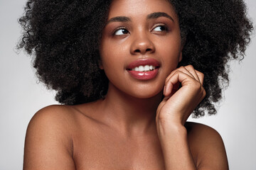 Smiling black lady with perfect skin looking away in studio
