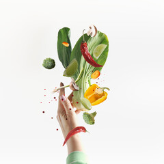 Flying vegetarian food ingredients with women hand at white background. Bok choi, mushrooms, bell pepper, chili pepper, broccoli and lime levitating. Healthy eating concept. Front view.