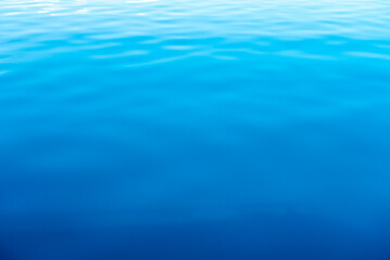 Obraz premium Clear water texture in blue and orange. Background of the ocean and the sea backlit by the sun. Natural water
