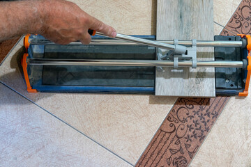 A worker uses a tile cutter to cut tiles to size.