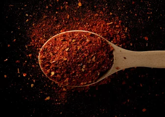Fotobehang Pittige chili peper vlokken, gemalen, gemalen droge paprika stapel in houten lepel geïsoleerd op zwart, bovenaanzicht © dule964