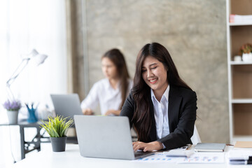 beautiful focused woman working with laptop while sitting at table in office,