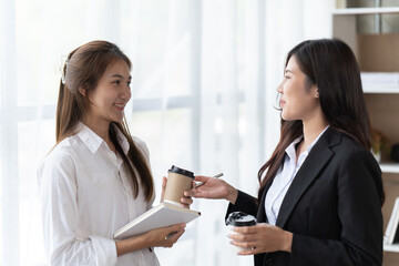 Two asian business woman, talking, advising each other in office, training team people speaking explaining strategy at marketing workshop concept.