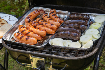 Outdoor barbecues. Sausages, black pudding, onions and baked bread on the grill. Food baked on...