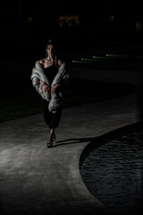 Fototapeta na wymiar fashion model walking by the side of the pool , black dress and elegant fur, high heels