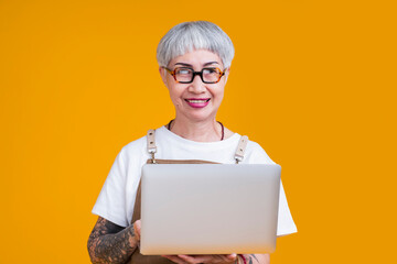 senior old female tattoo business owner wear apron hand hold laptop portrait smile,online marketing for small business senior asian female receive order from online shop purchase smart technology