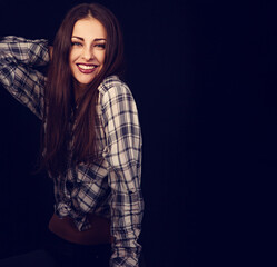 Beautiful happy toothy laughing student woman in plaid shirt on black background with empty copy space. Closeup portrait of natural happiness. Front