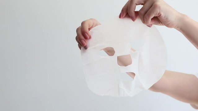 cosmetic sheet mask in hands on white background