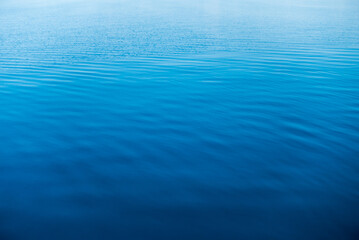 Clear water texture in blue and orange. Background of the ocean and the sea backlit by the sun. Natural water