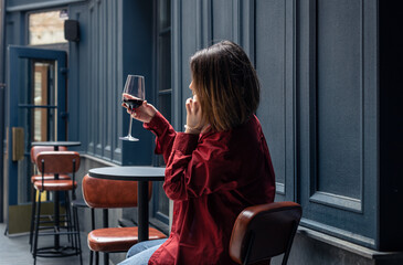 A young woman with a glass of wine on the terrace of a restaurant.