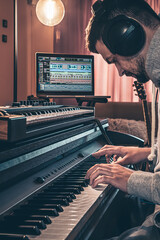 A male musician plays the musical keys in headphones. - obrazy, fototapety, plakaty