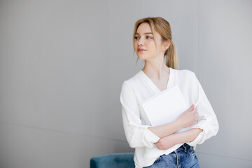 Fototapeta premium Young blonde woman in blouse holding notebook at home.