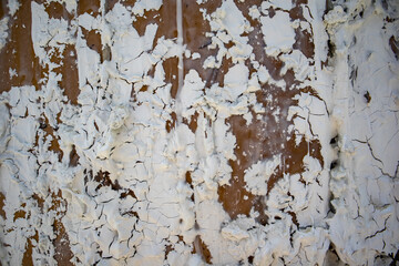 Abstract background texture of white wall with peeling paint, plaster. The dilapidated surface needs repair. Peeling cracked weathered paint. Scaled grunge surface. Vintage architecture details.