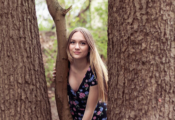 portrait of a beautiful young european girl 16 years old with long brown hair in nature, looking...